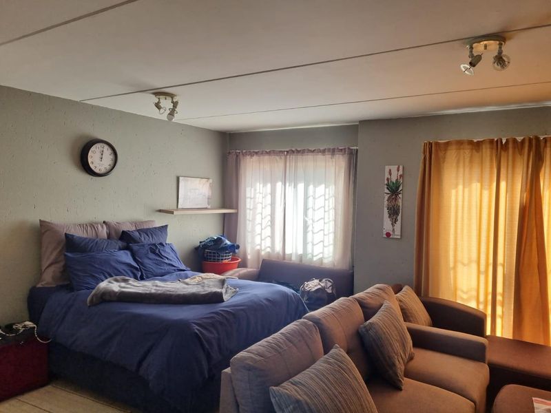 A bedroom featuring a sliding door leading to an outdoor area, neutral wall finishes, and ceiling-mounted spotlight fixtures.