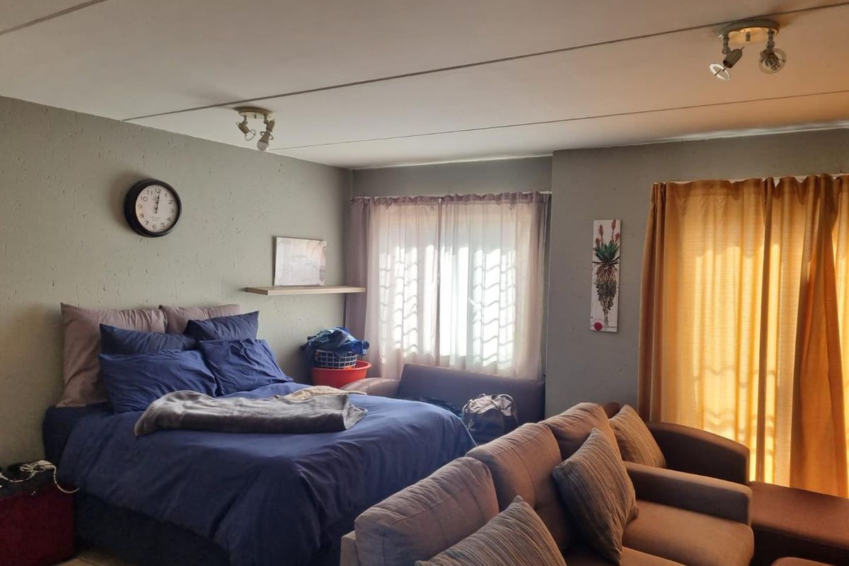 A bedroom featuring a sliding door leading to an outdoor area, neutral wall finishes, and ceiling-mounted spotlight fixtures.
