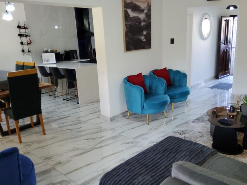 Spacious open-plan living and dining area featuring polished marble-look floor tiles and a modern kitchen island, creating a bright and cohesive living space.