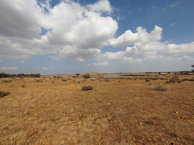 A wide-angle view of the expansive, undeveloped residential land featuring natural dry vegetation and open terrain under a cloudy sky.