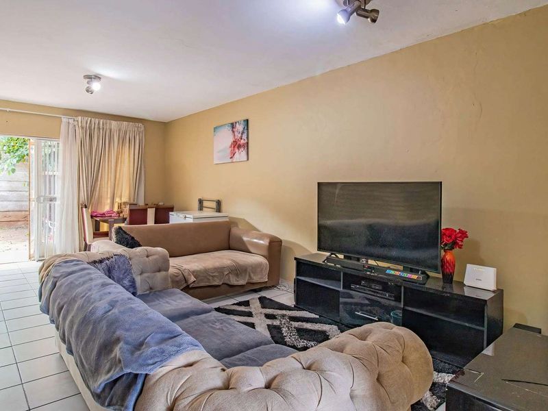 A living room featuring tiled flooring and a sliding glass door providing access to an outdoor area, with neutral wall finishes.