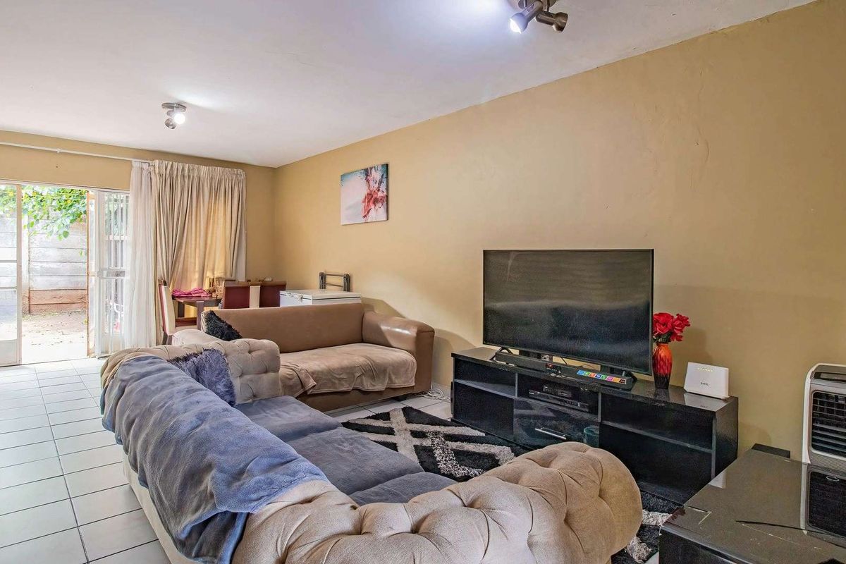 A living room featuring tiled flooring and a sliding glass door providing access to an outdoor area, with neutral wall finishes.