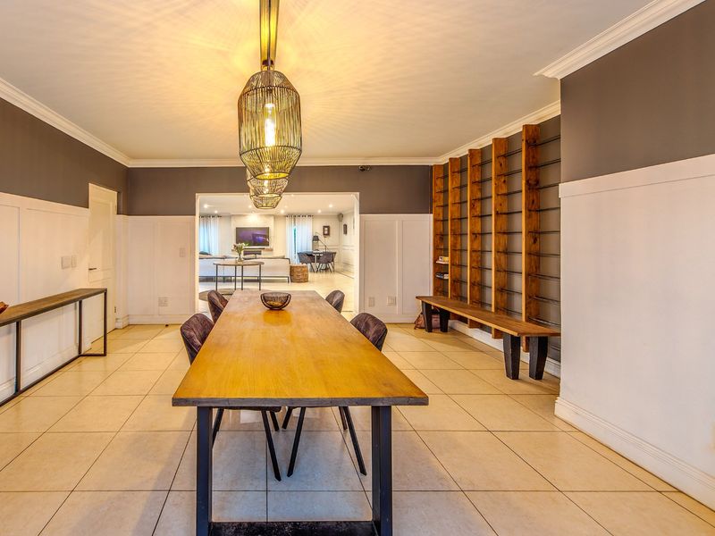 Spacious dining room featuring elegant wainscoting, crown molding, tiled flooring, and custom built-in shelving, creating a warm and inviting atmosphere for entertaining.