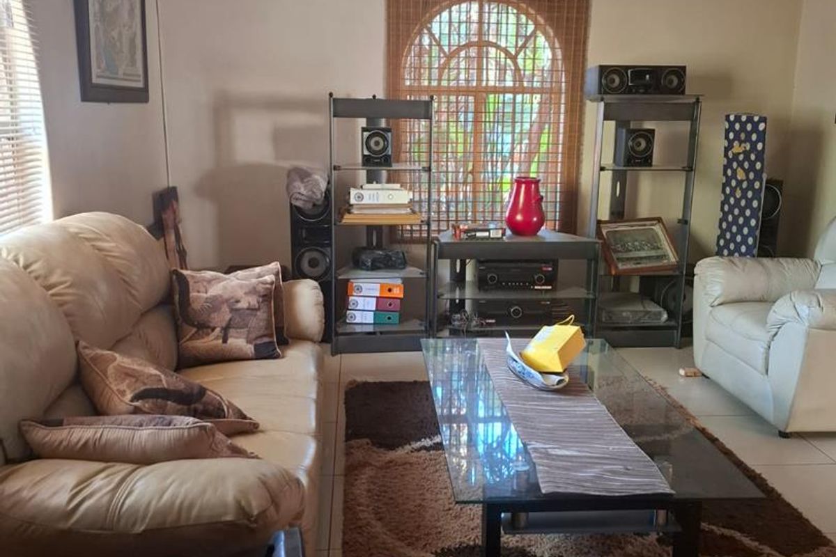 A comfortable living room featuring tiled flooring, an arched window with blinds, and crown molding, providing a functional and inviting space.