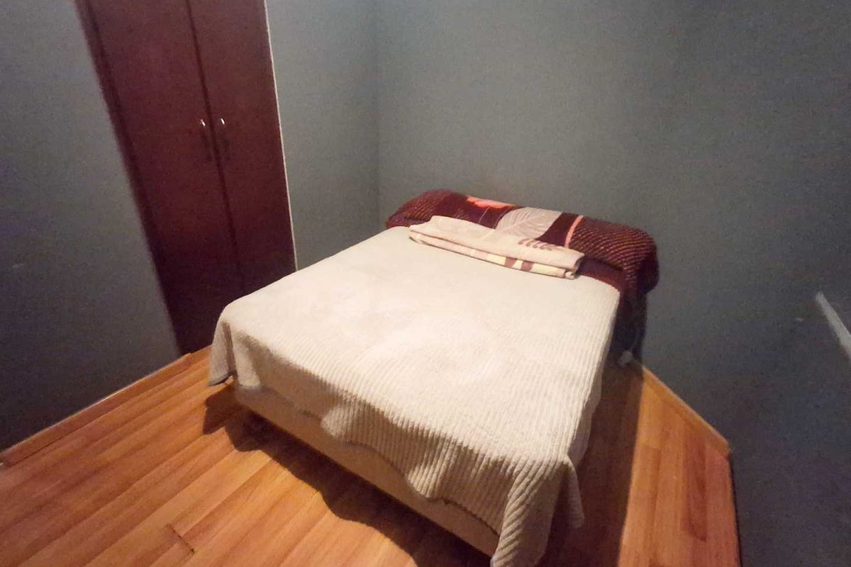 A bedroom featuring laminate flooring and a built-in wardrobe with dark-toned walls.