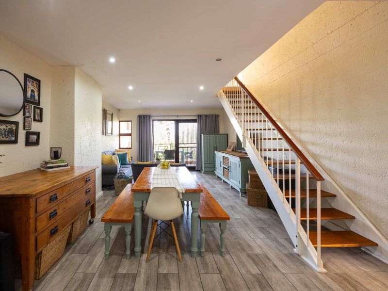 Open-plan living and dining area featuring modern tiled flooring, recessed lighting, and a staircase leading to the upper level.