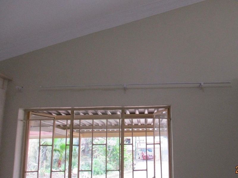 A bright living area featuring a vaulted ceiling, decorative cornice, and a secure metal gate leading to the exterior.