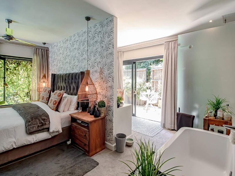 A modern bedroom suite featuring a partition wall, integrated bathroom area with a soaking tub, and sliding glass doors leading to a private patio.