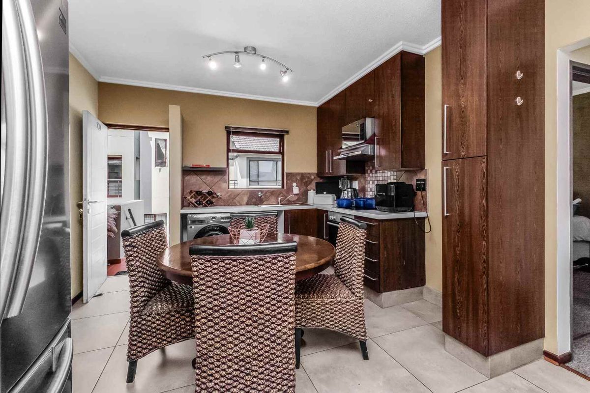 A functional kitchen featuring dark wood cabinetry, built-in appliances, tiled flooring, and a dedicated dining area with a tiled backsplash.