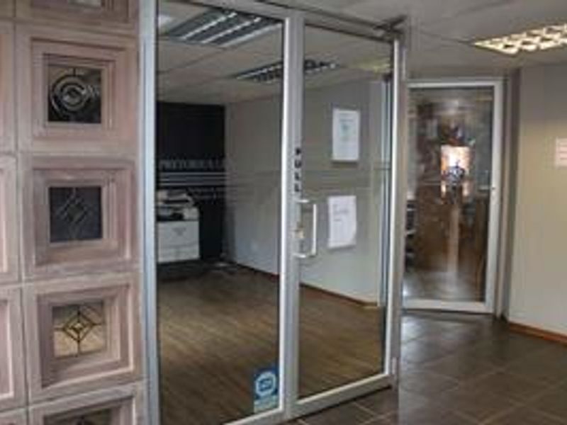 Professional office space featuring aluminium framed glass entry doors, recessed lighting, and durable tiled flooring, suitable for a modern corporate environment.