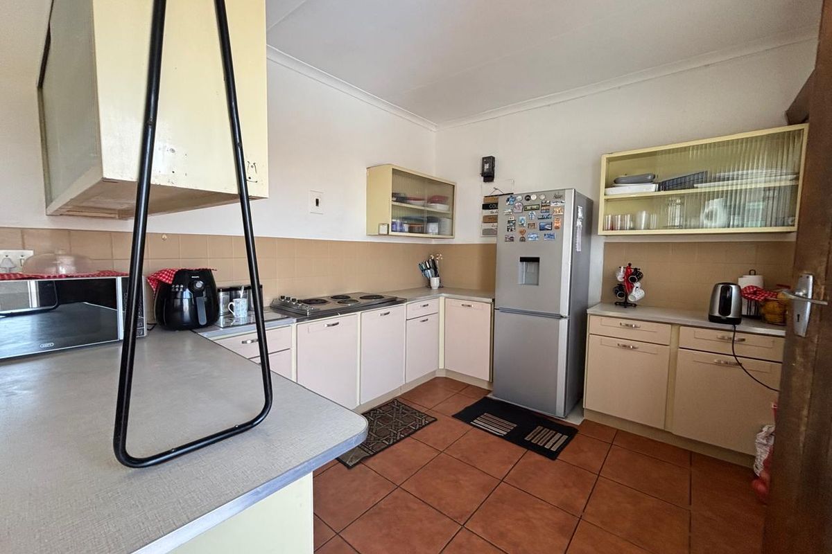 A functional kitchen featuring built-in cabinetry, laminate countertops, ceramic tile flooring, and a tiled backsplash, offering a dated but practical layout.