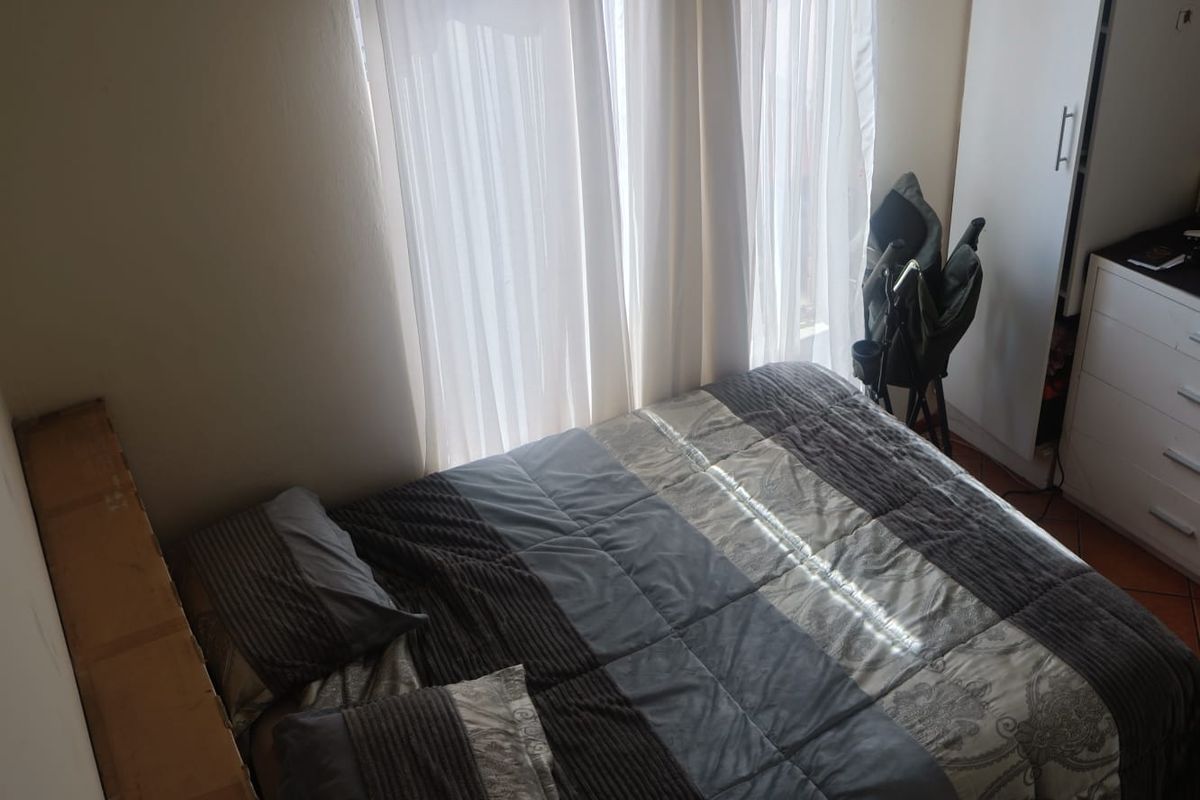 A bedroom featuring built-in cabinetry and large windows with sheer curtains, providing natural light.