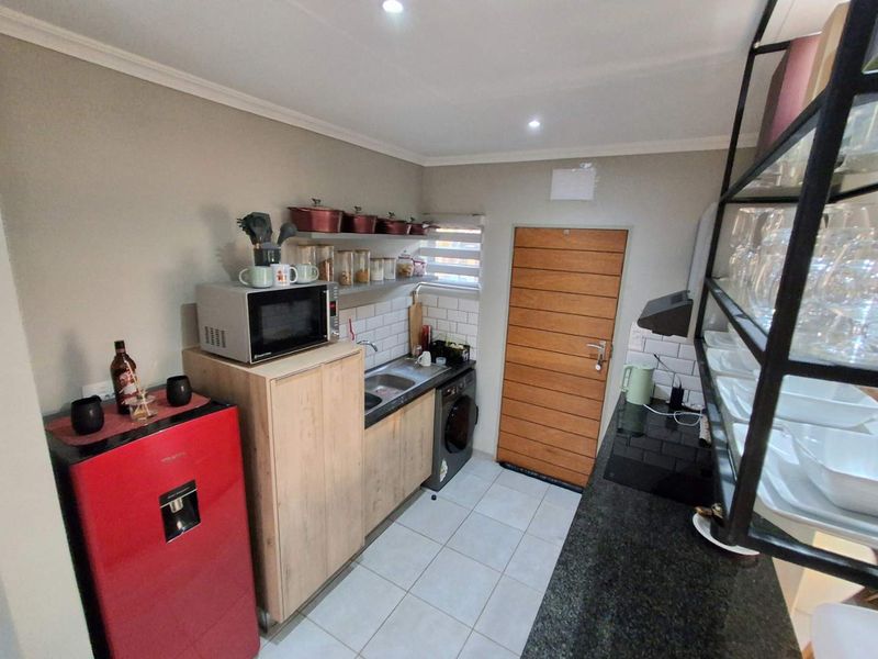 A compact, well-maintained kitchen featuring modern cabinetry, granite countertops, subway tile backsplash, and integrated cooking appliances.