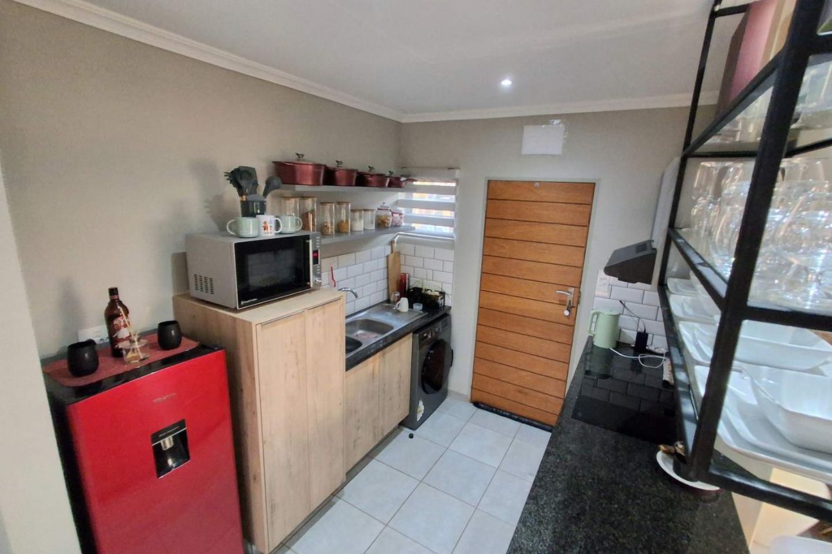 A compact, well-maintained kitchen featuring modern cabinetry, granite countertops, subway tile backsplash, and integrated cooking appliances.