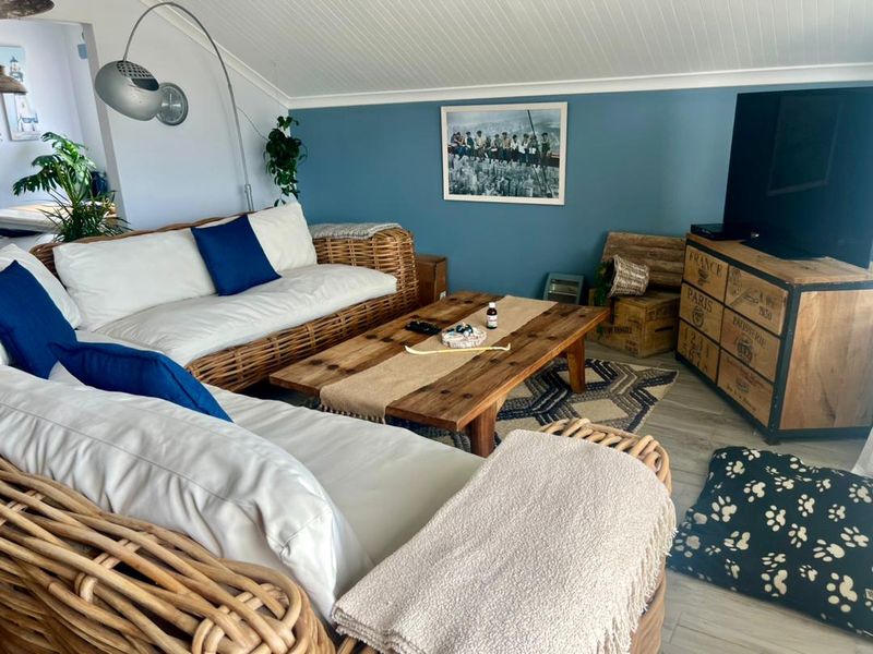 A cozy living room featuring a sloped tongue-and-groove ceiling, blue accent wall, and light-toned flooring.