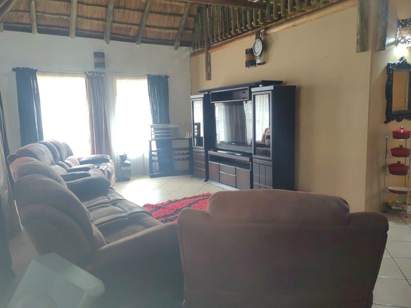 Spacious living room featuring a traditional thatched roof with exposed timber rafters and tiled flooring.
