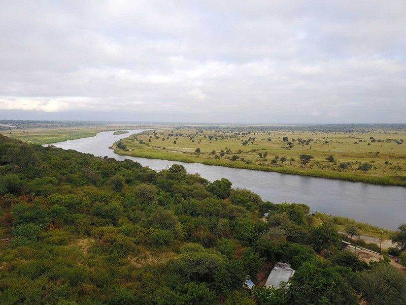 A scenic aerial view overlooking a winding river flowing through a vast, natural savanna landscape.