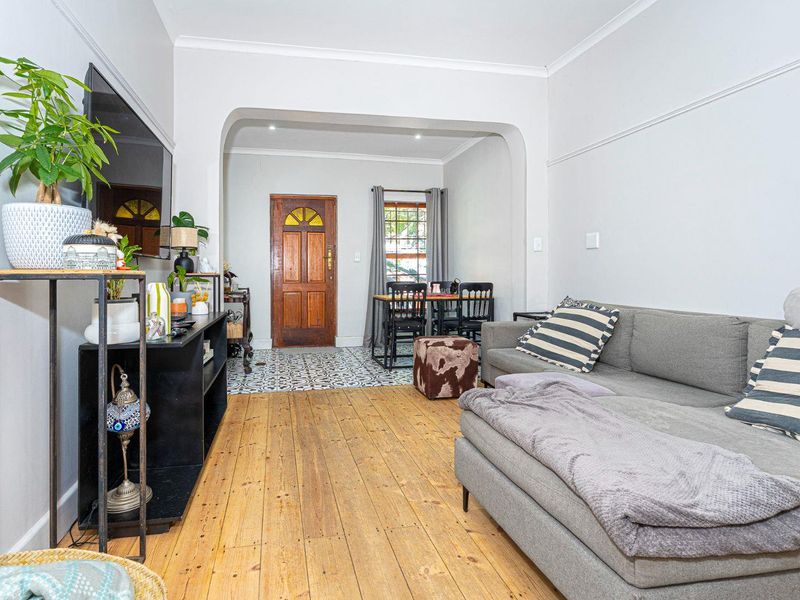 Open-plan living area featuring polished hardwood floors, a distinct arched transition to the entryway, and decorative patterned floor tiles.