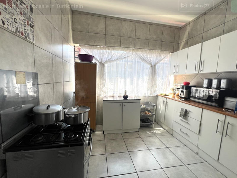 A functional kitchen featuring tiled walls and flooring, white built-in cabinetry, and a gas stove with ample counter space.