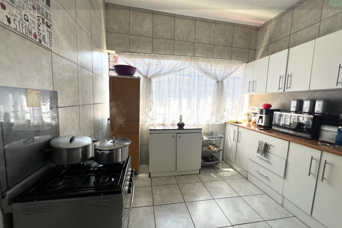 A functional kitchen featuring tiled walls and flooring, white built-in cabinetry, and a gas stove with ample counter space.
