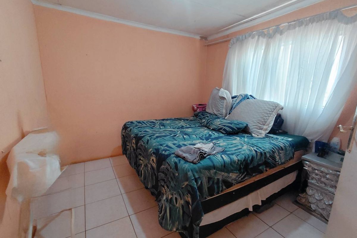 A bedroom featuring tiled flooring and plain walls, requiring cosmetic updates to improve the overall aesthetic and finish.