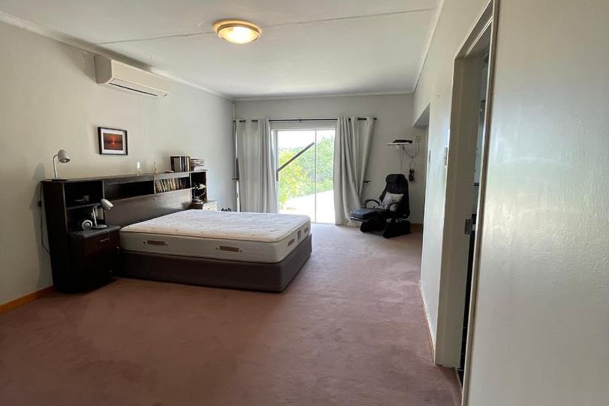 Spacious bedroom featuring neutral walls, wall-mounted air conditioning unit, and sliding glass doors providing access to an outdoor area.