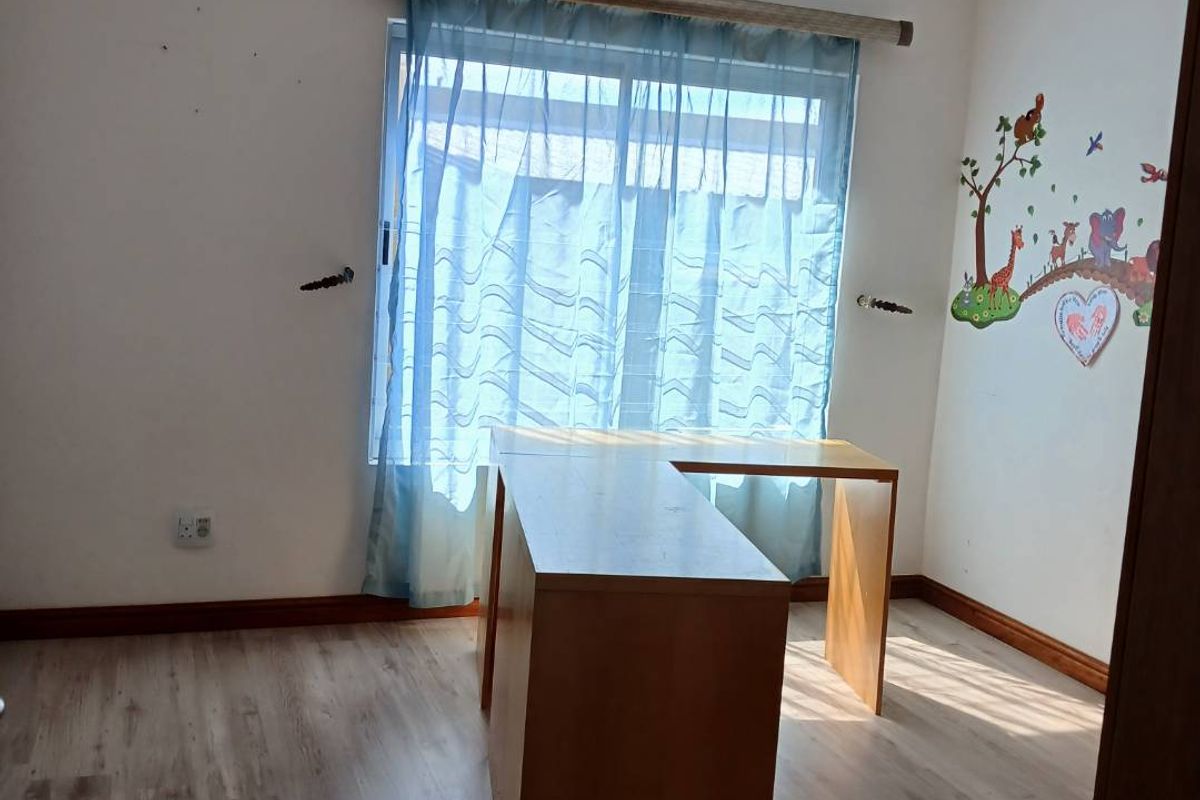 A bedroom featuring laminate flooring, a wall-mounted air conditioning unit, and a sliding window with natural light.