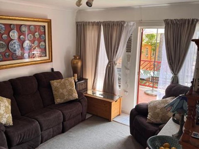 A comfortable living room featuring tiled flooring and a sliding glass door providing access to an outdoor balcony area.