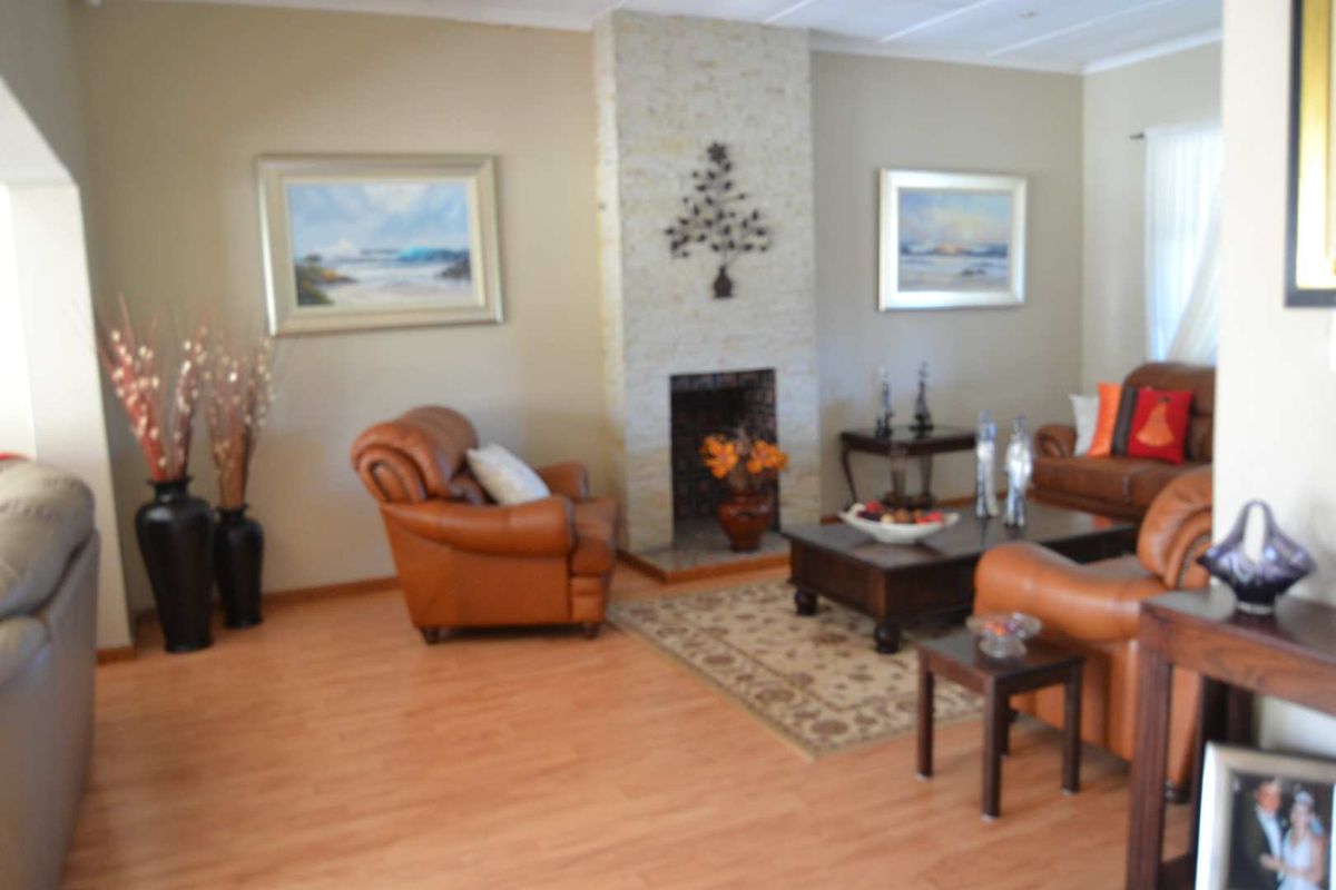 A comfortable living room featuring a central stone-clad fireplace as a focal point, complemented by warm-toned laminate flooring.