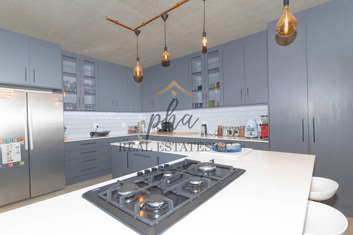 Modern kitchen featuring grey cabinetry, white subway tile backsplash, stone countertops, and a central island with a built-in gas hob.