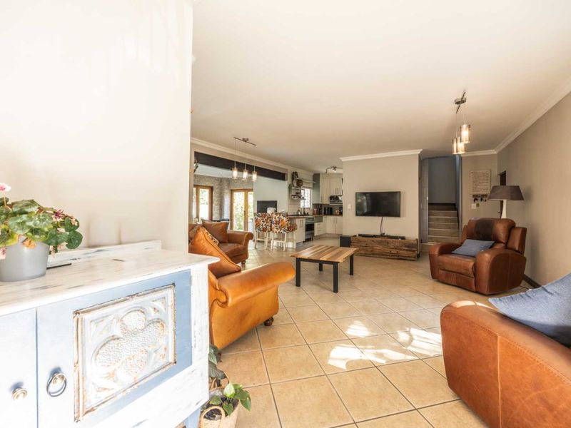 Spacious open-plan living area featuring tiled flooring, integrated kitchen cabinetry, and a staircase, creating a functional and connected family living space.
