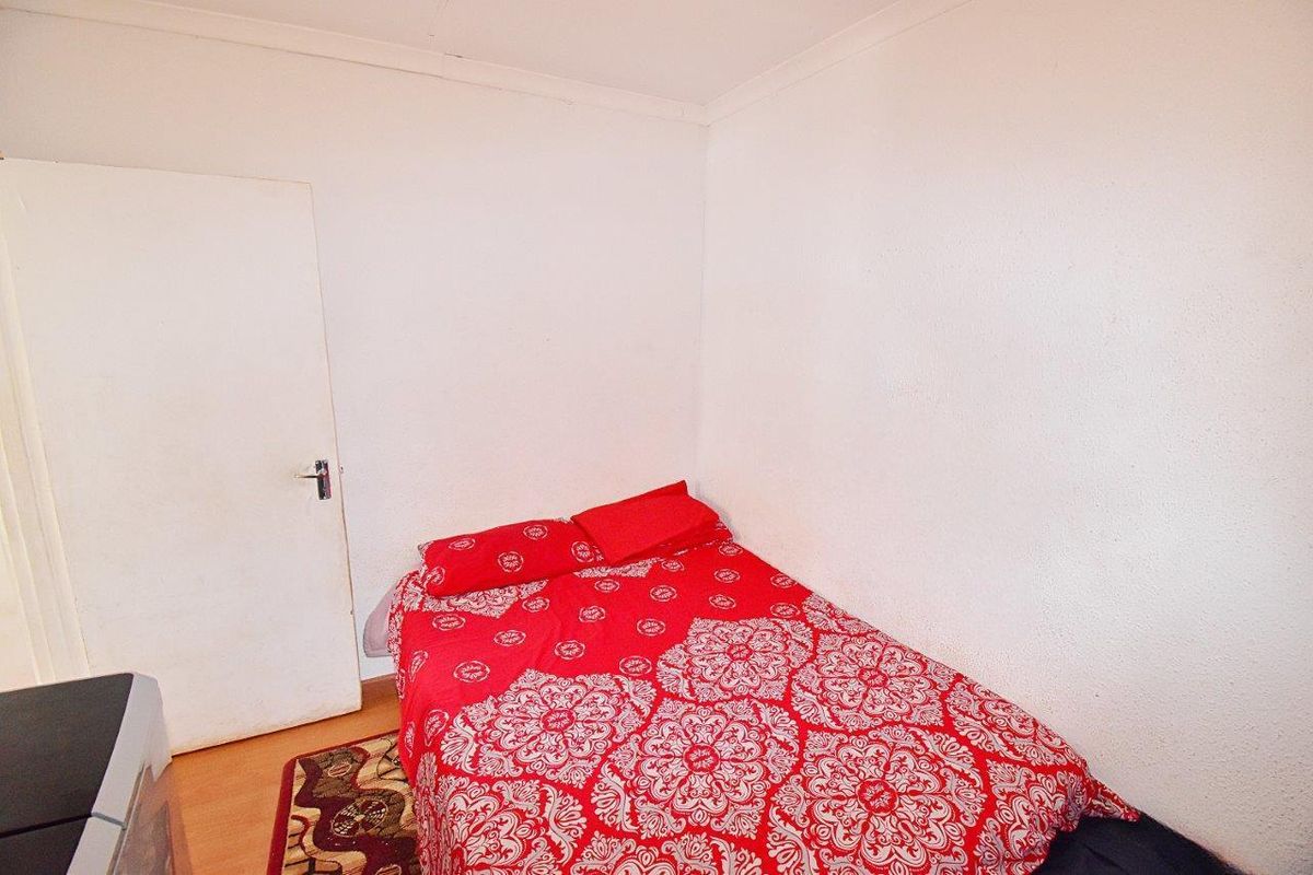 A simple bedroom featuring laminate flooring and a standard interior door.