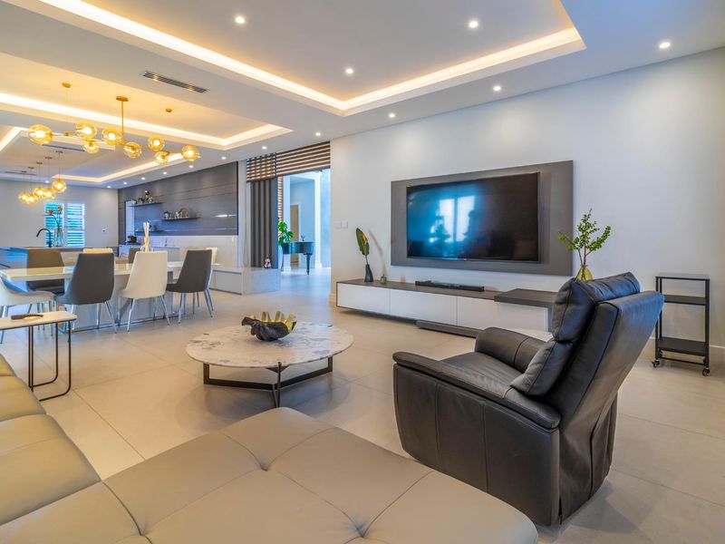 Spacious open-plan living and dining area featuring modern recessed lighting, a sleek built-in media wall, and a contemporary kitchen with a central island.