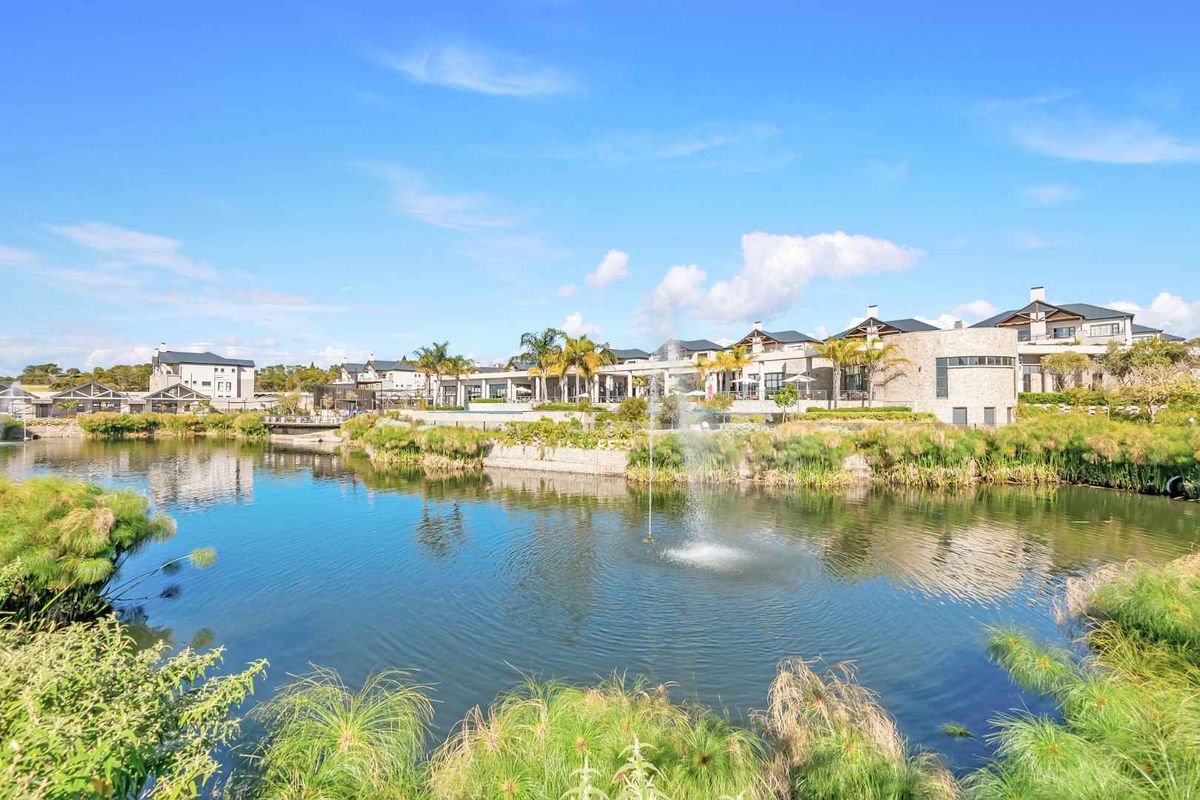 A scenic view of the apartment complex exterior featuring a landscaped pond with a central water fountain and well-maintained building facades.