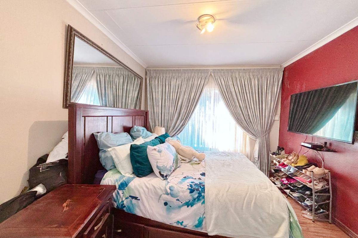 A bedroom featuring a large window with curtains, a feature wall, and ceiling-mounted lighting.