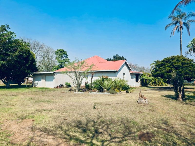 A view of the rear elevation of the house featuring a tiled roof, double garage, and a spacious garden area.