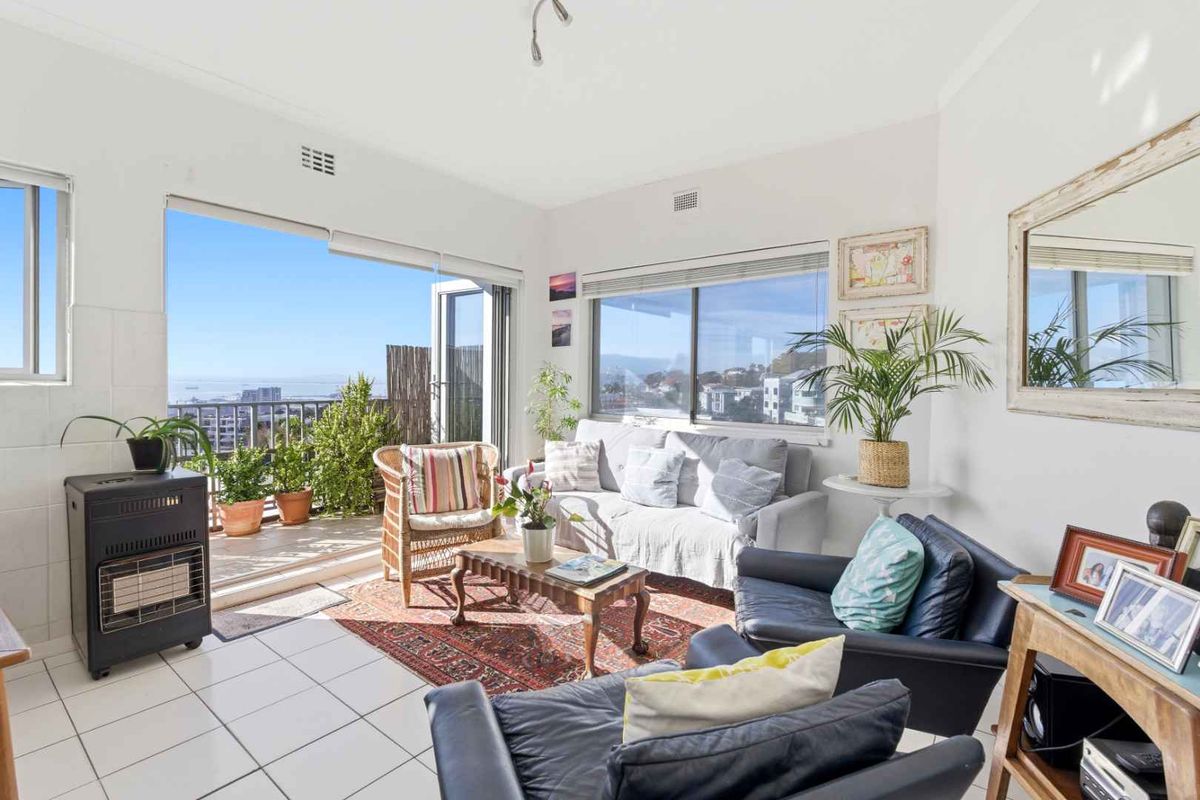 Bright living room featuring tiled flooring and large sliding glass doors that open onto a balcony with scenic views.