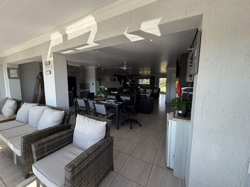 Spacious open-plan living area featuring tiled flooring, recessed lighting, and a ceiling fan, seamlessly connecting indoor and outdoor living spaces.