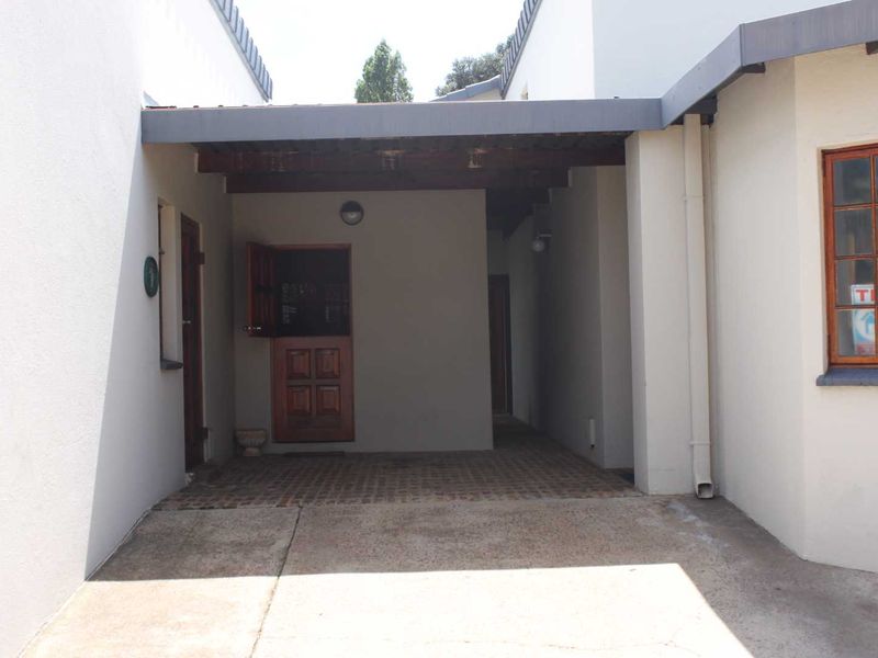 A covered rear patio area featuring brick paving, a timber pergola structure, and a classic stable-style door entrance.