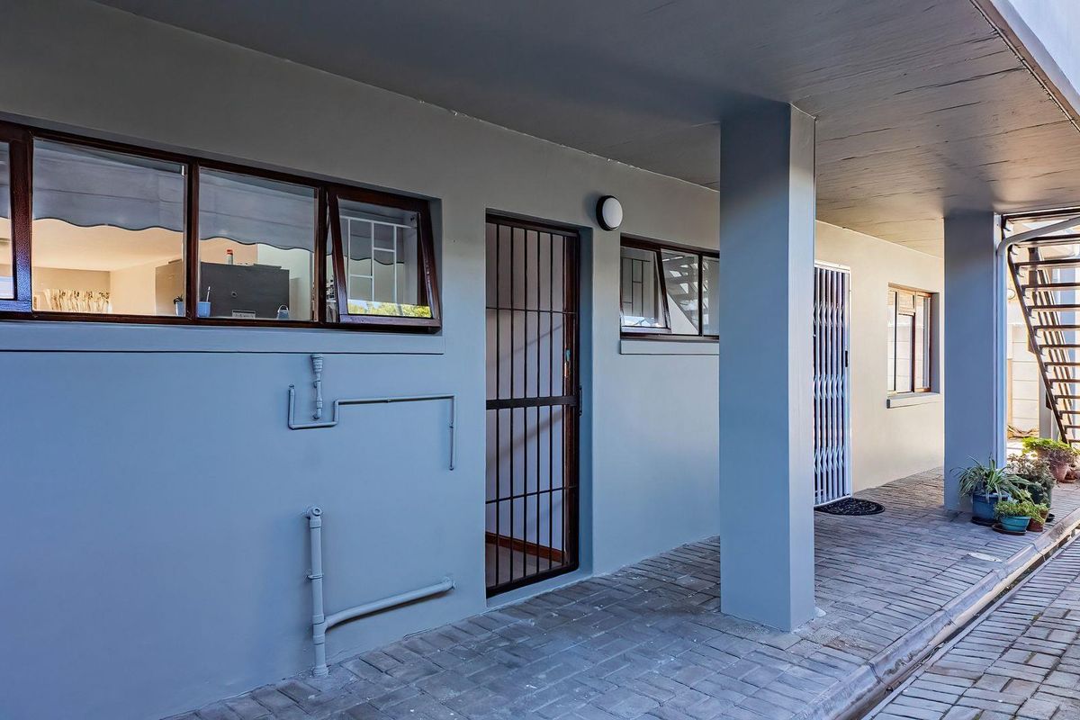 A well-maintained exterior walkway featuring paved flooring, security gates, and access to an external metal staircase.