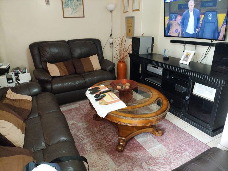 A comfortable living room featuring tiled flooring and a wall-mounted television setup.