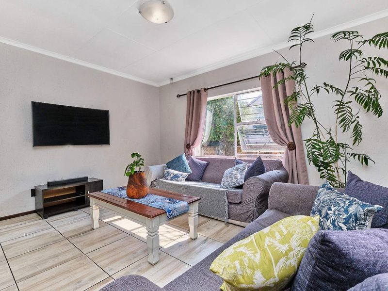 A comfortable living room featuring tiled flooring, neutral wall finishes, and a large window allowing for natural light.