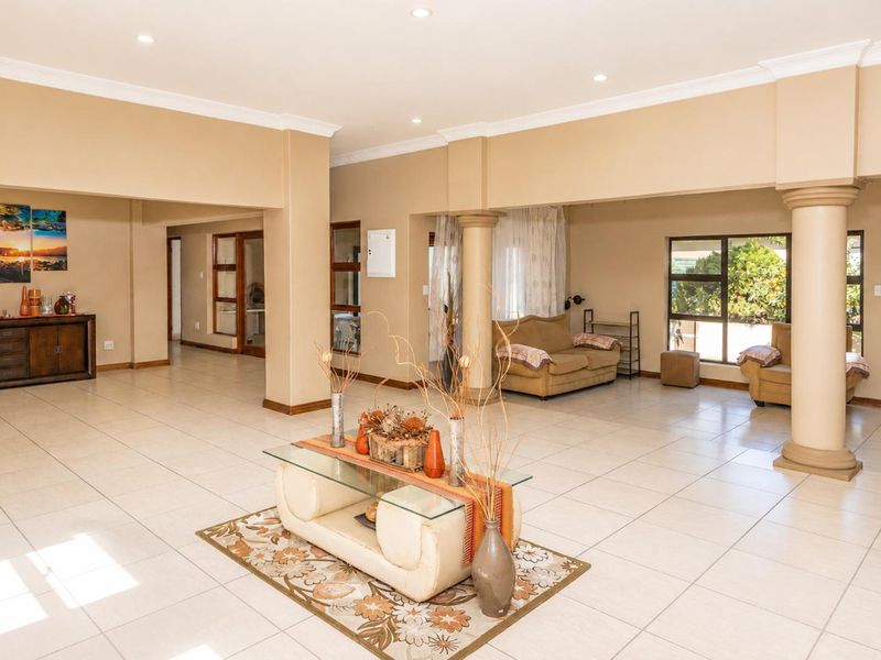 Spacious open-plan living area featuring neutral tiled flooring, structural columns, and recessed downlighting, offering a versatile layout for multiple living configurations.