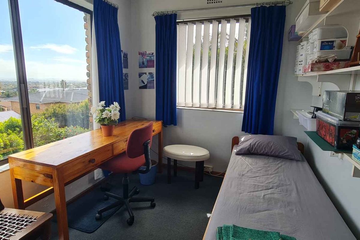 A bedroom featuring large windows with natural light, carpeted flooring, and built-in shelving units.
