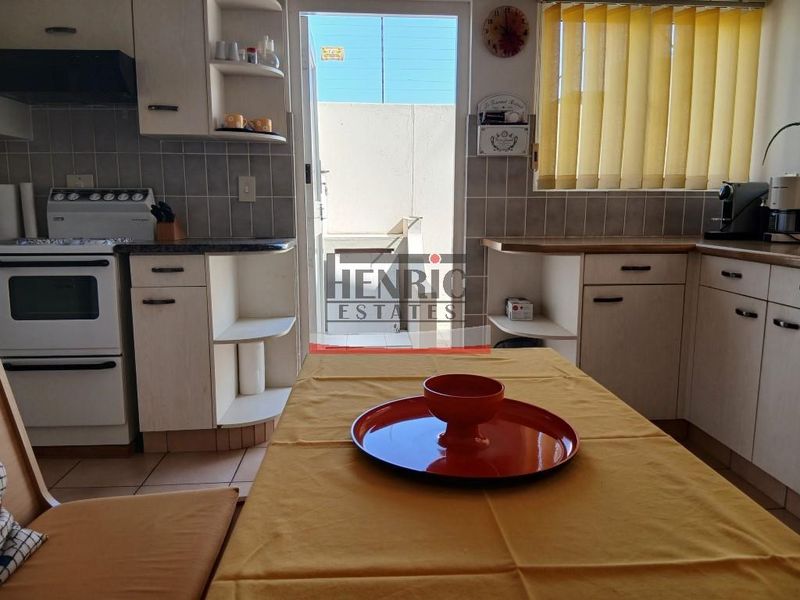 A functional kitchen featuring built-in cabinetry, tiled backsplash, and a freestanding stove, with direct access to an outdoor area.