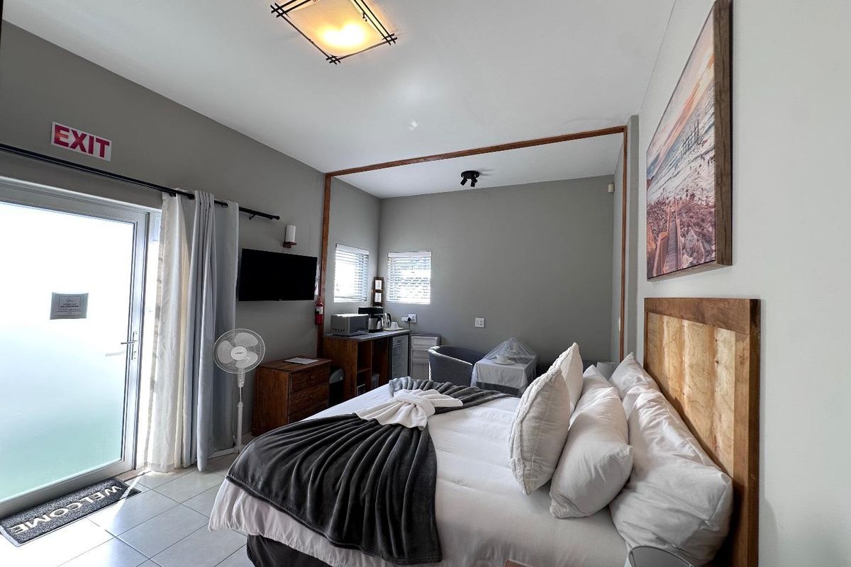 A well-lit bedroom featuring tiled flooring, a built-in headboard, and direct access to an outdoor area through a glass door.