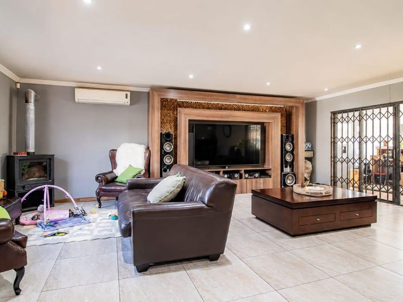 Spacious living room featuring a built-in media unit, wood-burning fireplace, split-system air conditioning, and tiled flooring with access to a secure patio area.