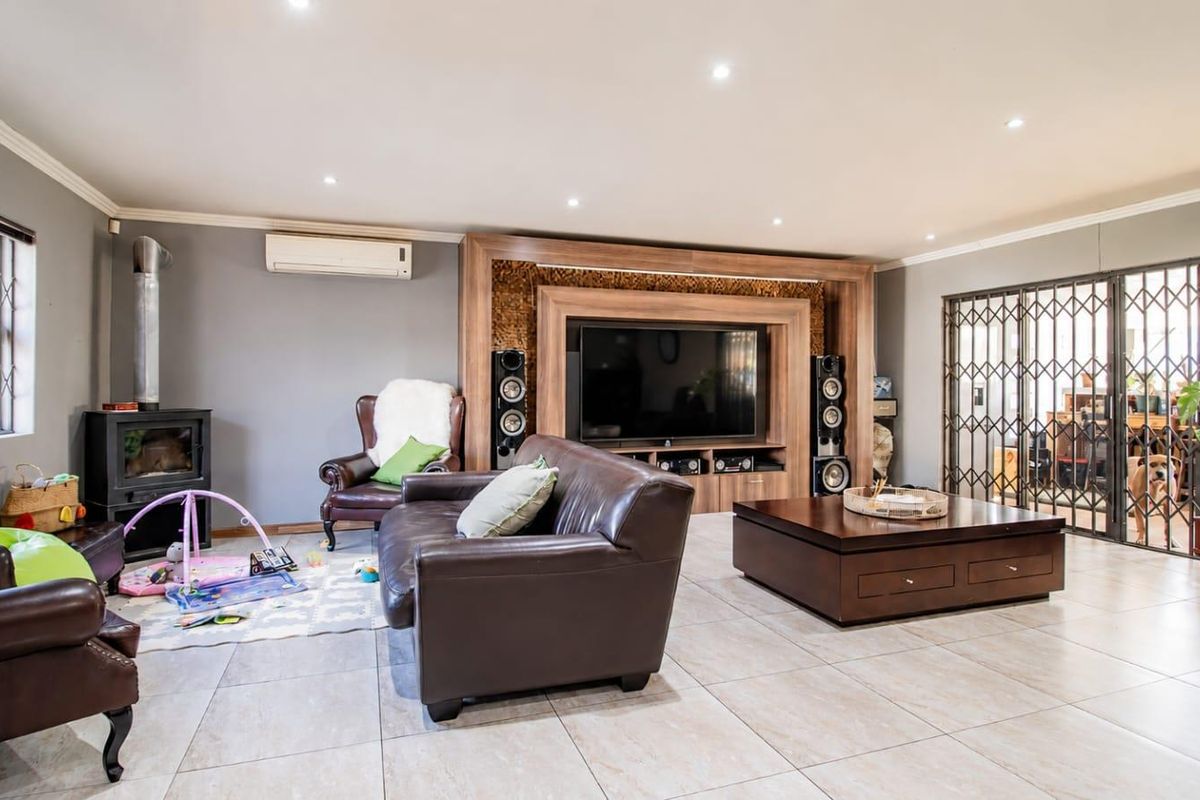Spacious living room featuring a built-in media unit, wood-burning fireplace, split-system air conditioning, and tiled flooring with access to a secure patio area.