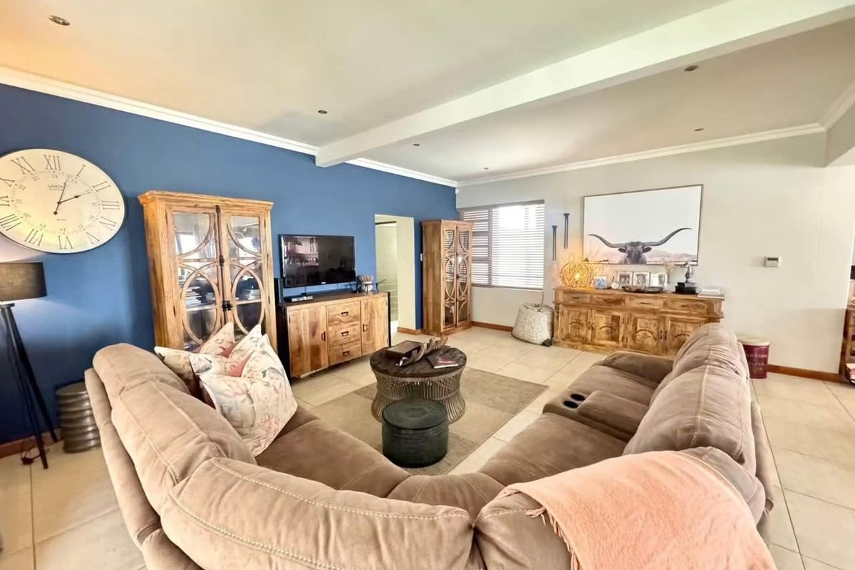 Spacious living room featuring tiled flooring, recessed downlighting, and a bold blue accent wall, creating a comfortable and inviting atmosphere.