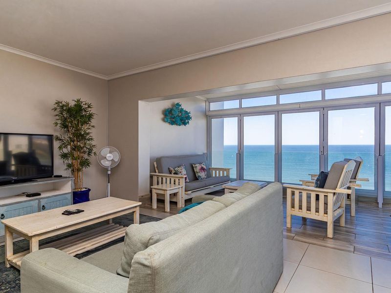 Spacious living area featuring a wood-burning stove and large glass sliding doors that open to a balcony with expansive ocean views.